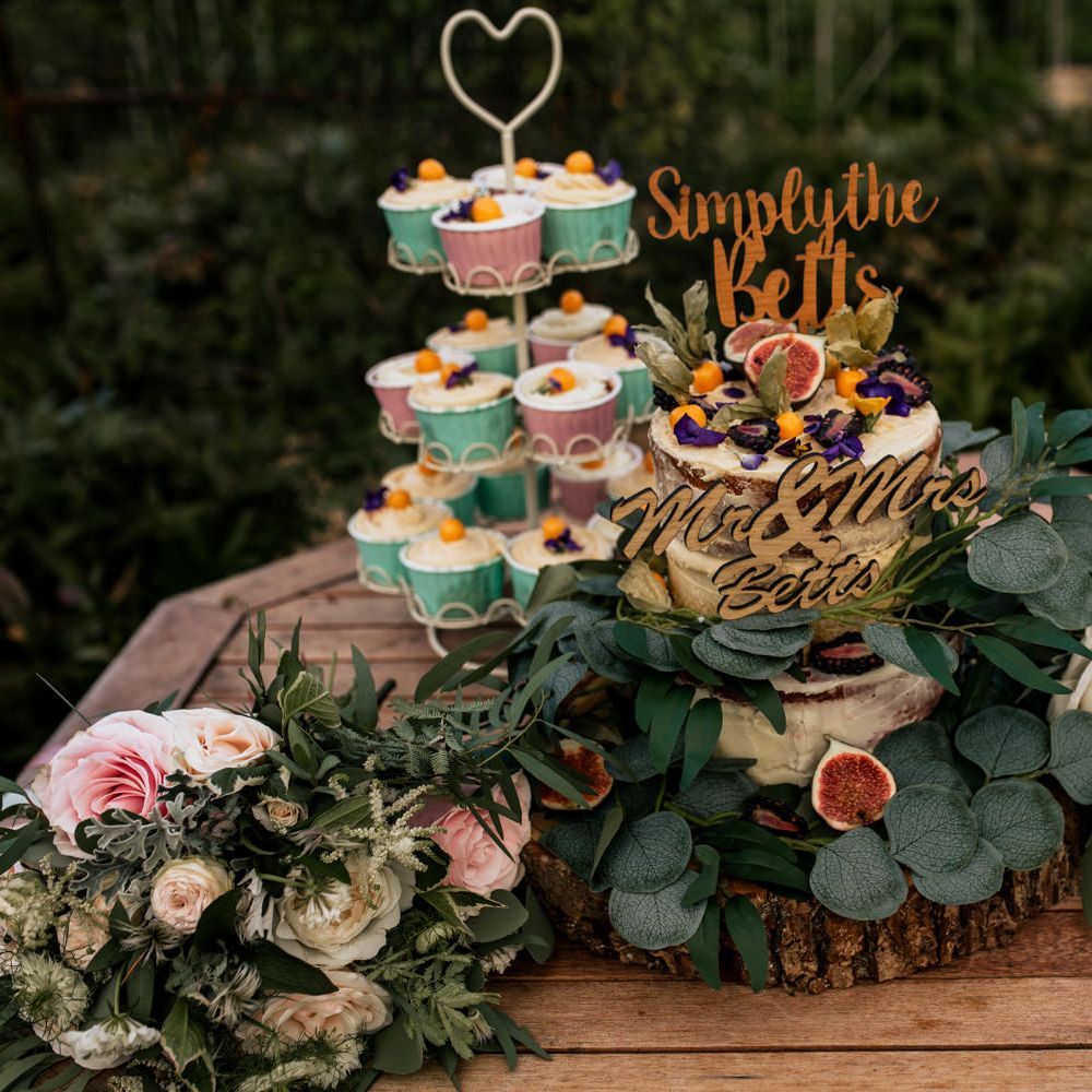 Wedding cake and cupcakes with floral foliage surrounding