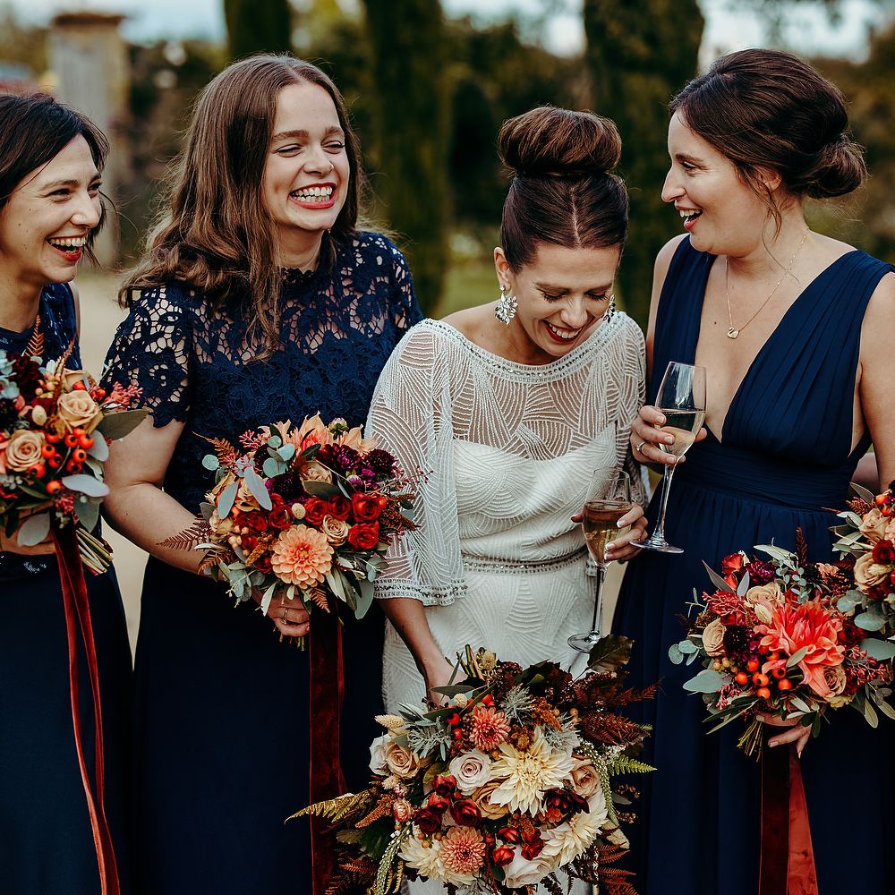 Bride stands with her bridesmaids in deep blue dresses 