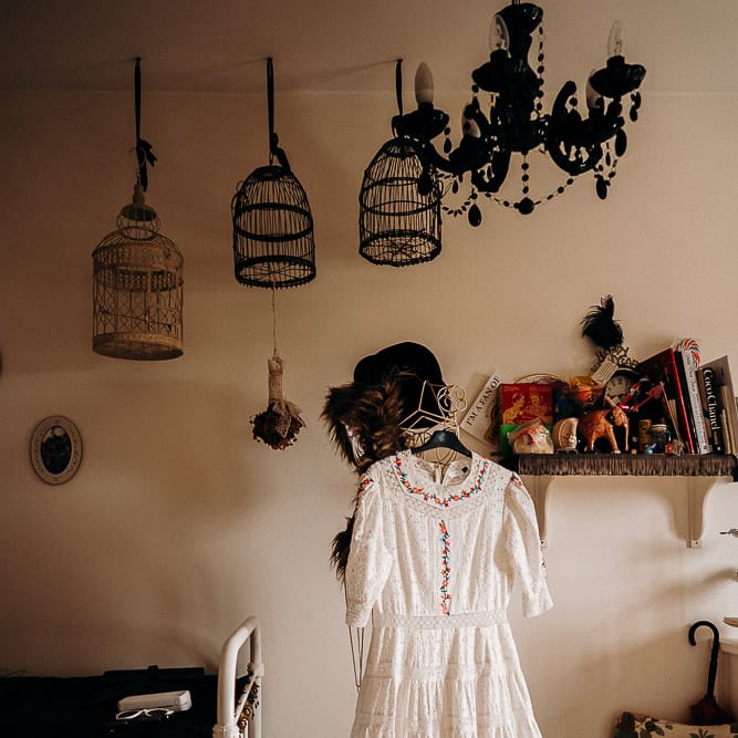 Broderie Anglaise wedding dress hanging up at home 