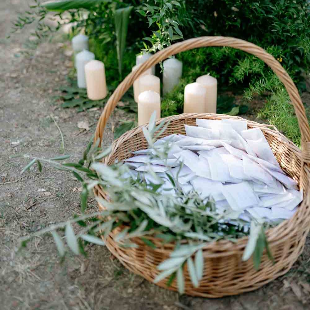 Candles and foliage surround a wicker basket with confetti pouches in 