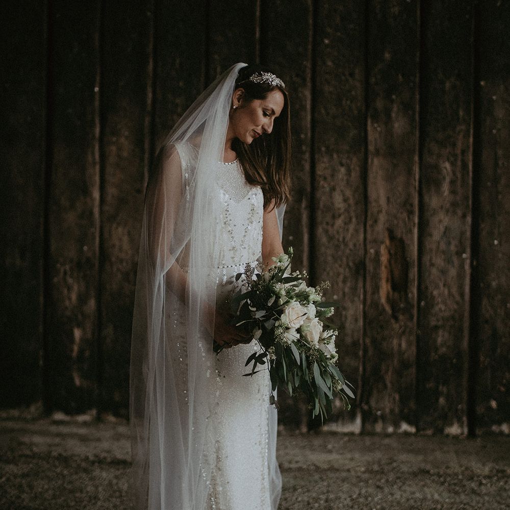 Bride looks down on her wedding day as she holds floral bouquet