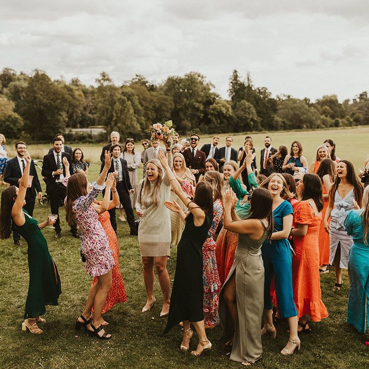 Wedding guests catch bridal bouquet outdoors
