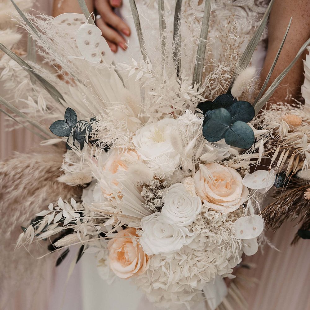 Bride holds floral bouquet filled with pastel coloured flowers