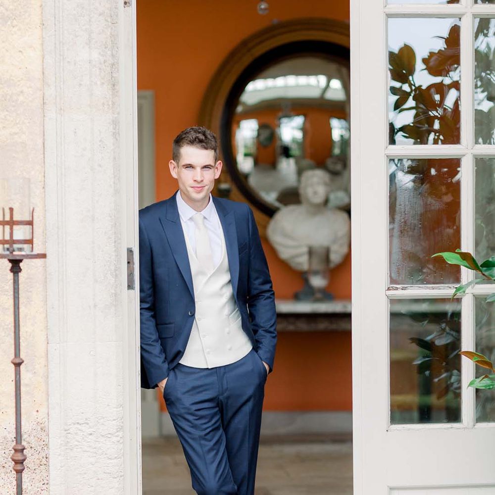 Groom leans on door at The Orangery 
