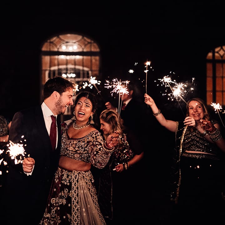 Groom & Bride hold sparklers at the evening of their wedding at Minley Manor
