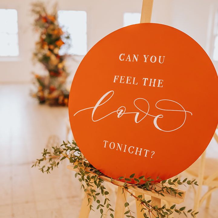 Orange circle wedding sign on a wooden easel at golden wedding 