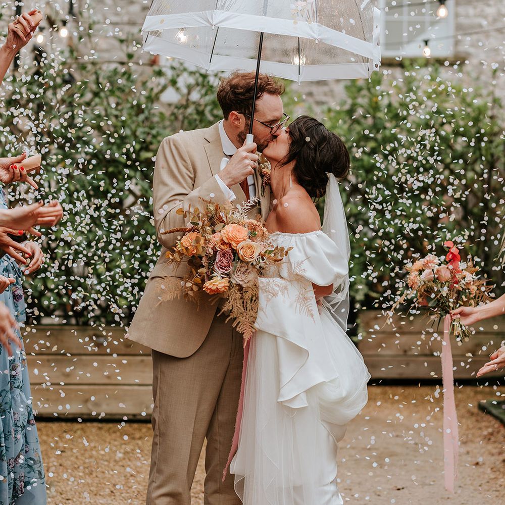 Bride and groom get their confetti exit with bride in Loeffler Randall wedding shoes and groom holding clear umbrella