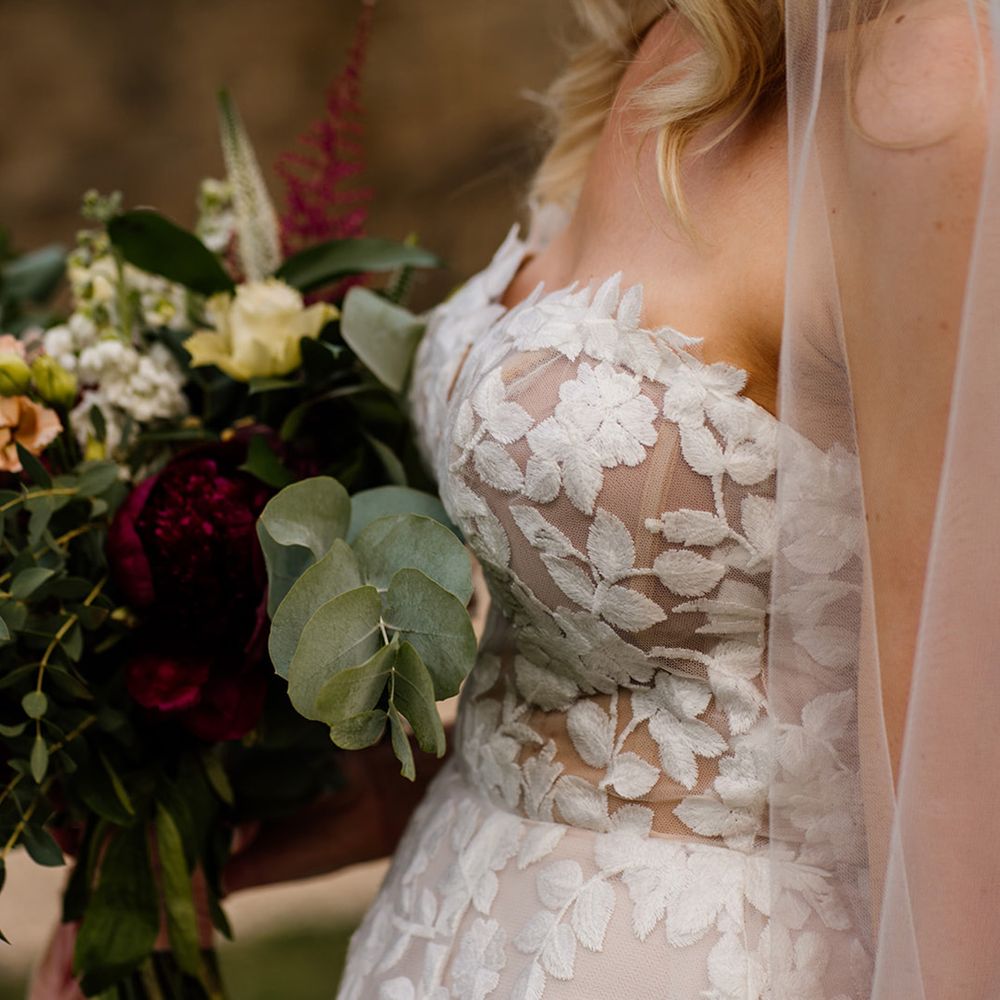 Bride in strapless lace Lillian West wedding dress with red and white flower wedding bouquet 