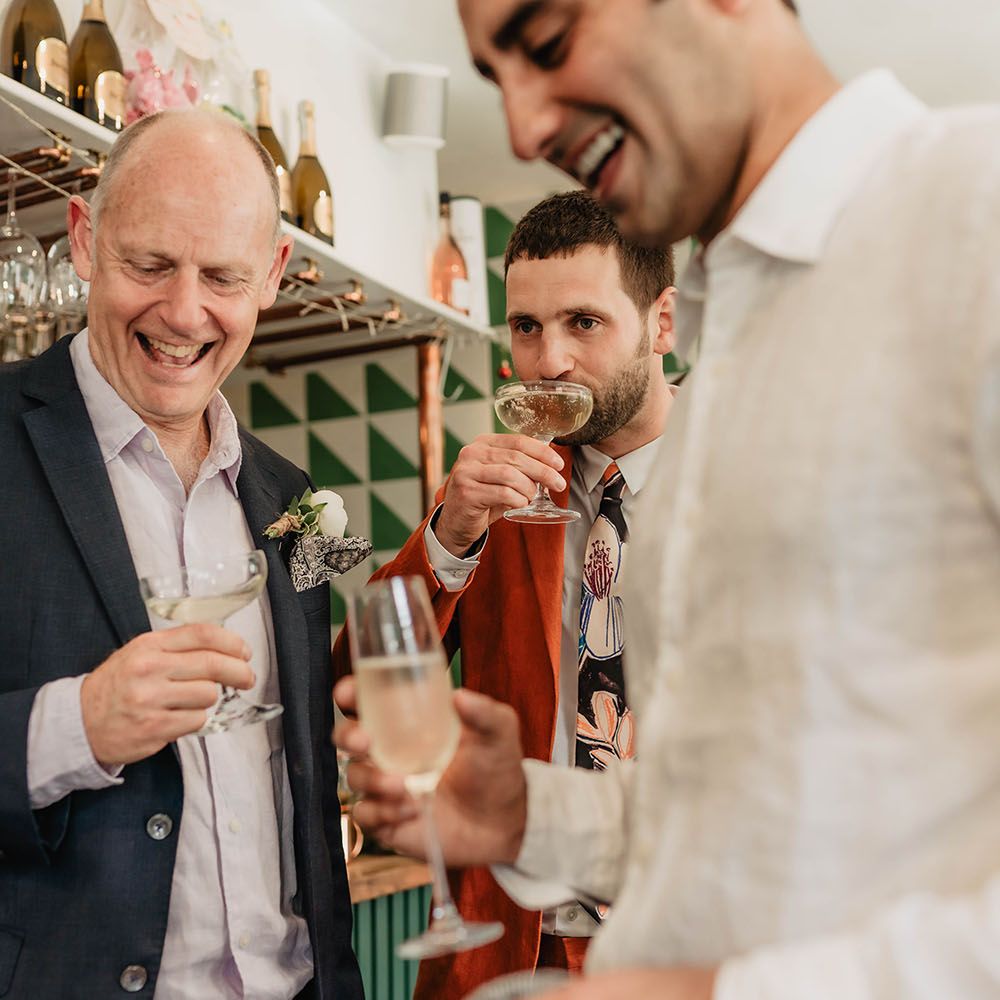 Wedding guests & groom sip Prosecco during wedding reception 