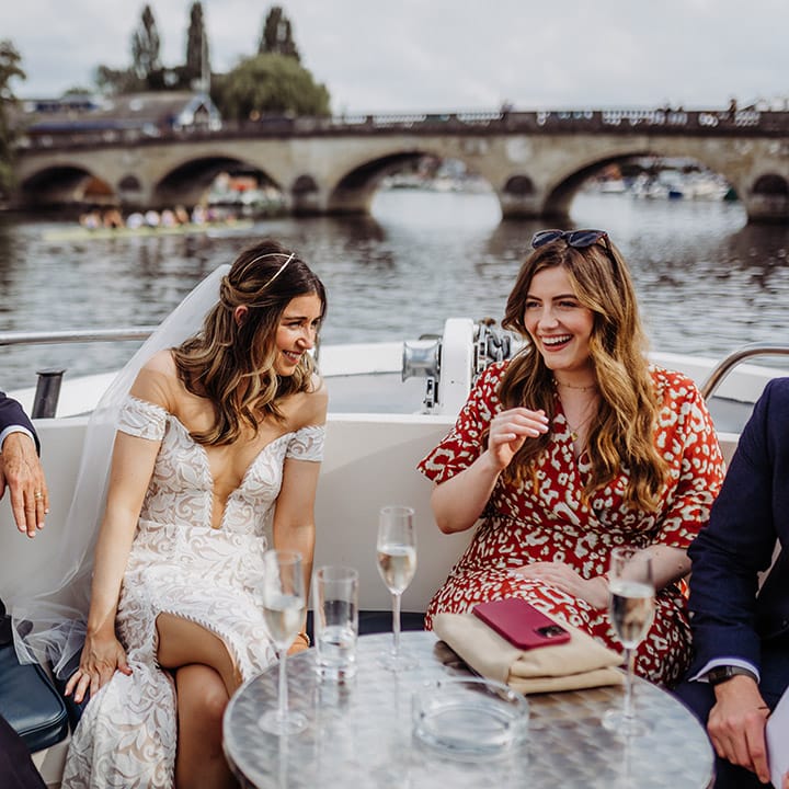 Bride laughs and socialises with wedding guests on a boat 