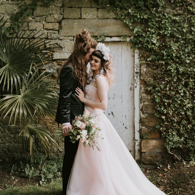 Spring wedding at Hooton Pagnell with bride in a pink strapless wedding dress and groom in a tuxedo embracing 