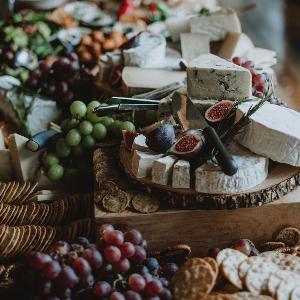 Wedding day grazing board with cheese, figs, crackers and grapes set on wooden boards across table