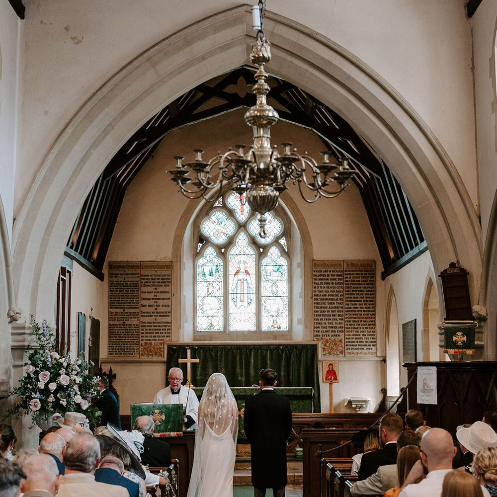 Bride wearing a flower applique veil standing at the altar with the groom for their church ceremony 