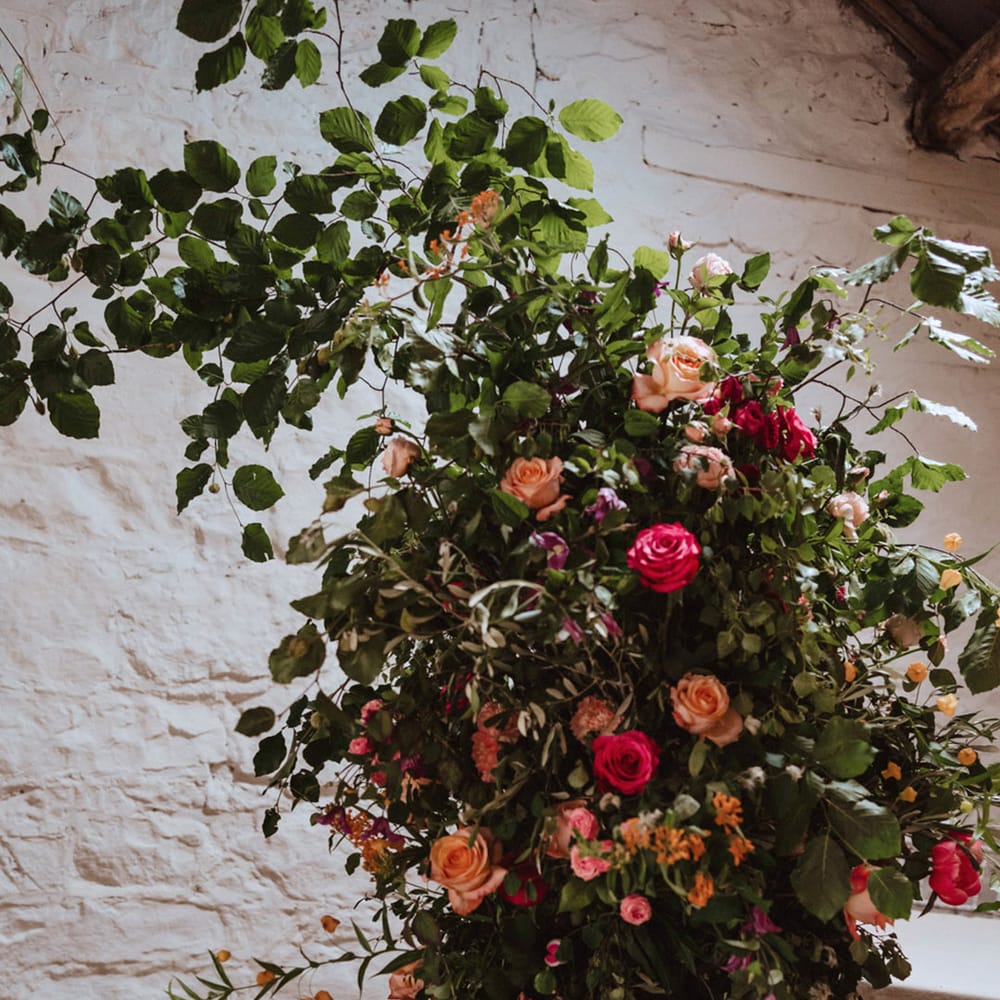 Close up of the blush pink and dark pink rose and peony wedding column flower arrangement decorating the altar at The Courtyard