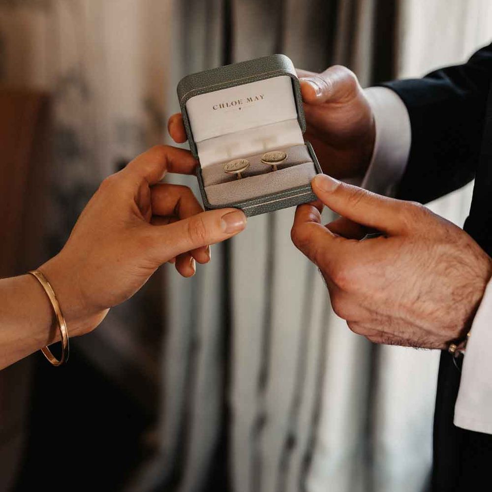 Bride and groom holding grey cufflinks box with personalised cufflinks inside 