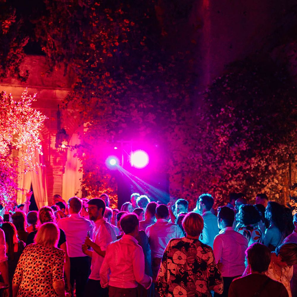 The wedding guests party at the wedding reception with colourful lights 