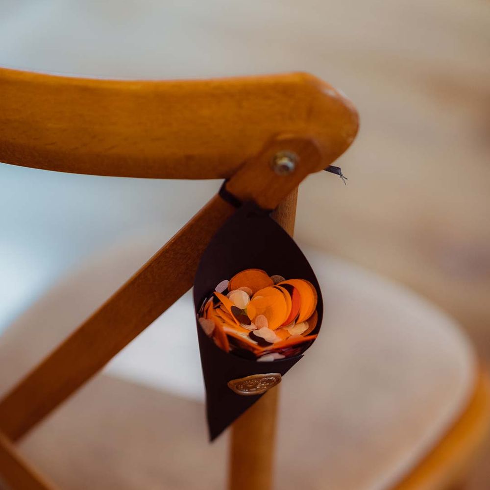 Confetti cone on the back of wooden chair at Kingscote Barn Tetbury wedding venue 