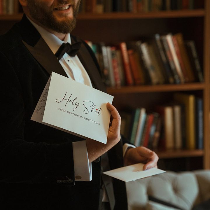 Groom in black tuxedo reading letter from the bride on the morning of the wedding 