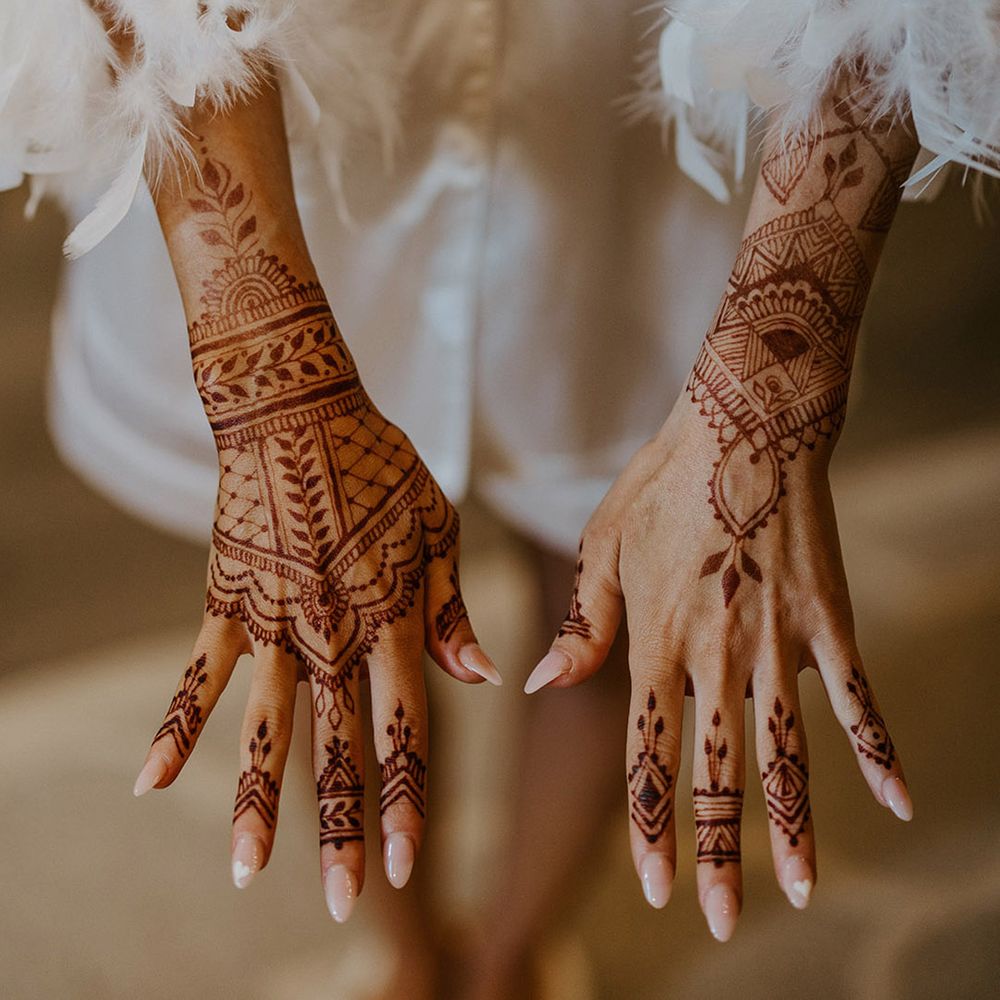 Bride shows off henna wedding design with neutral almond shaped wedding nails 