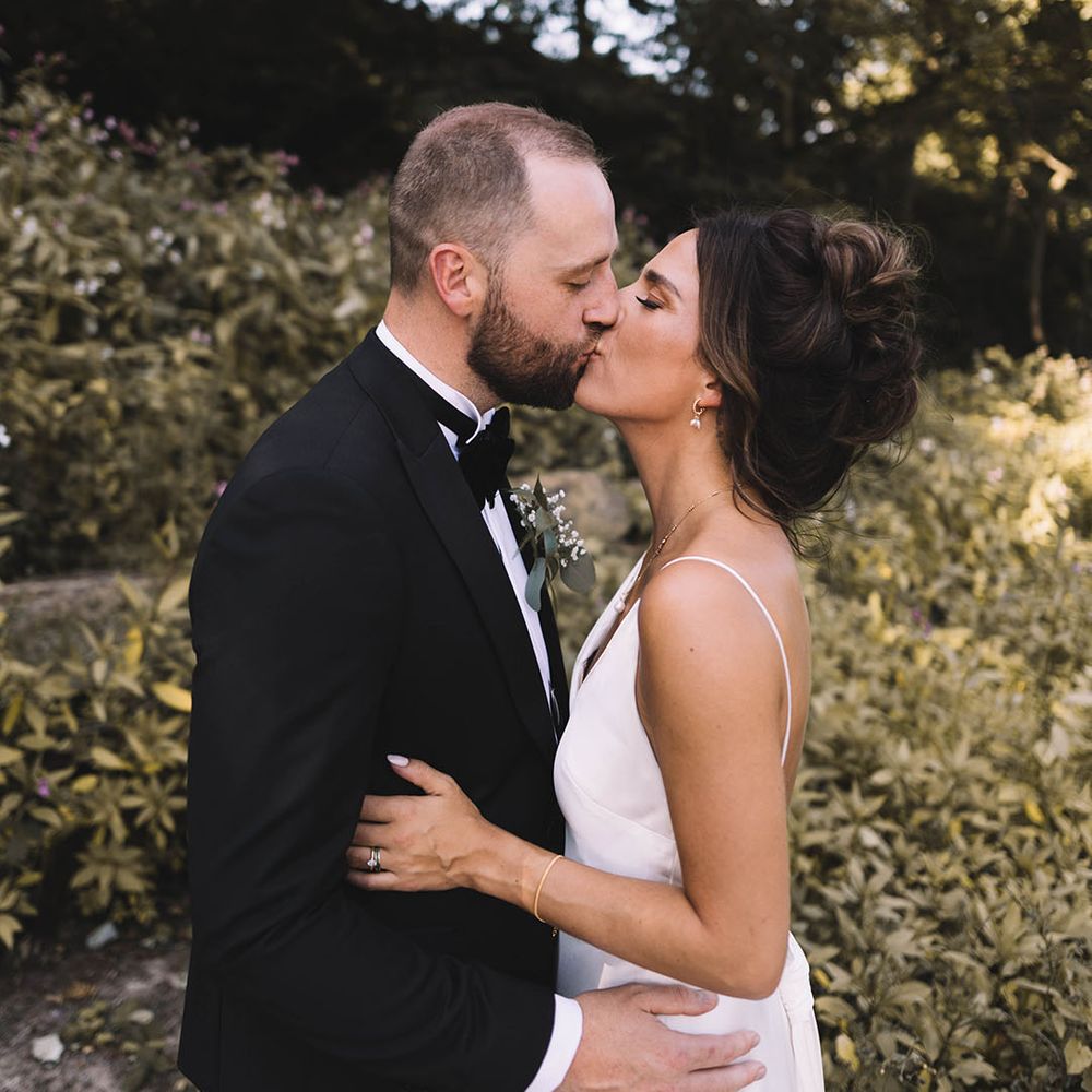 Bride in satin bridal gown kisses the groom in a black tuxedo at Bowers Mill 