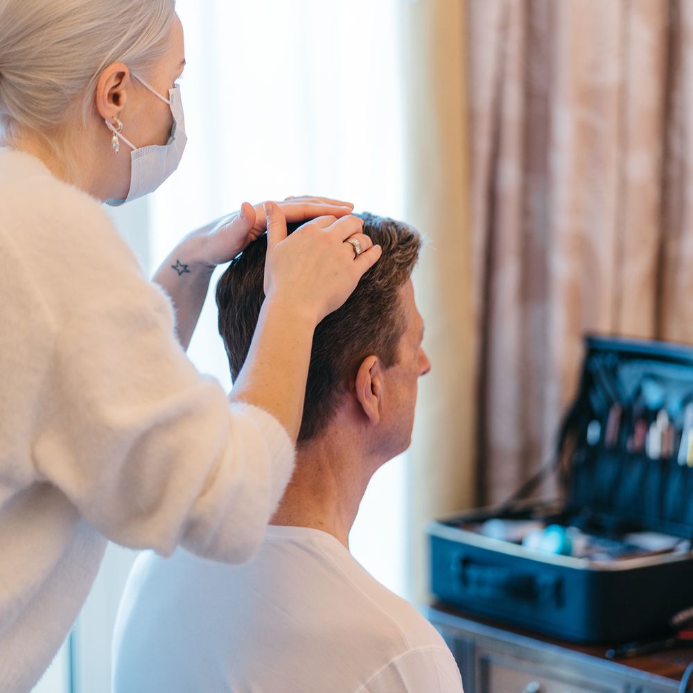 Groom has his hair done on the morning of his wedding