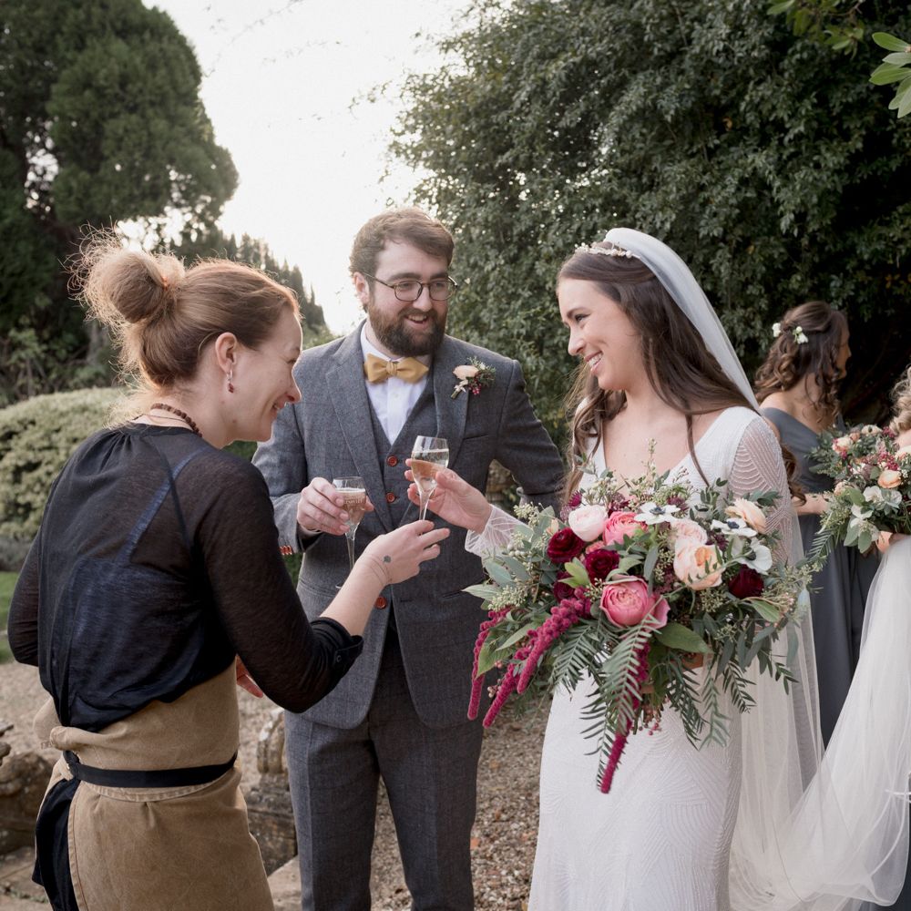 Newly married couple holding champagne glasses outside on their wedding day