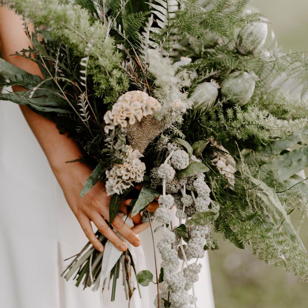 Tropical green wedding bouquet with ferns, dried poppy heads and celosias