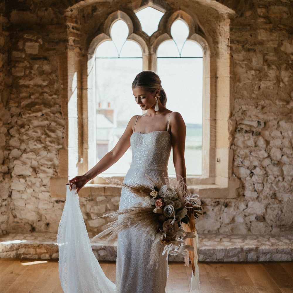Bride in a sparkly wedding dress standing in front of a window at Pentney Abbey, Norfolk