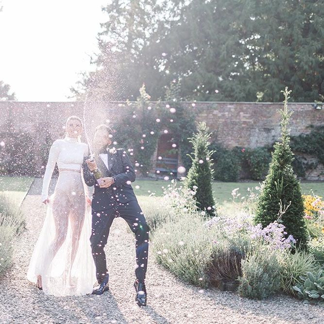 Bride and groom spraying champagne in the gardens at Garthmyl Hall wedding venue 