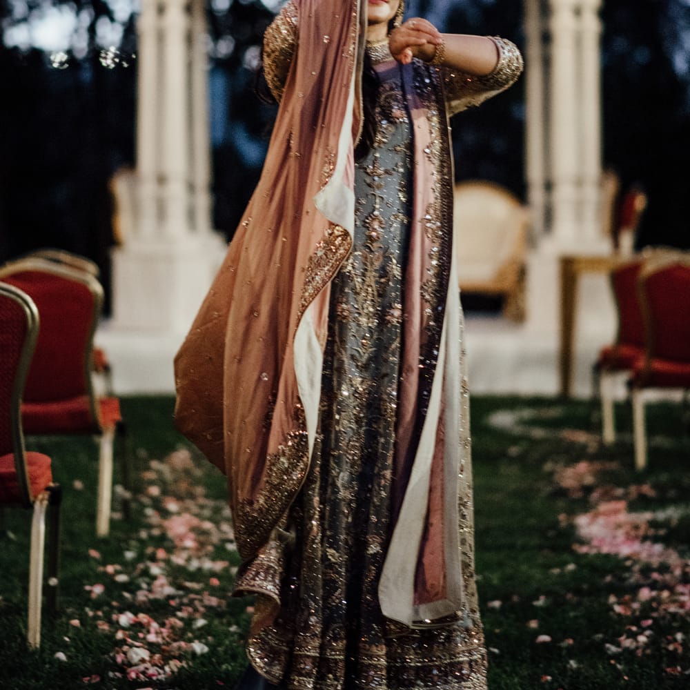 Bride wears beautiful and brightly coloured saree as she holds hand in the air showing her henna