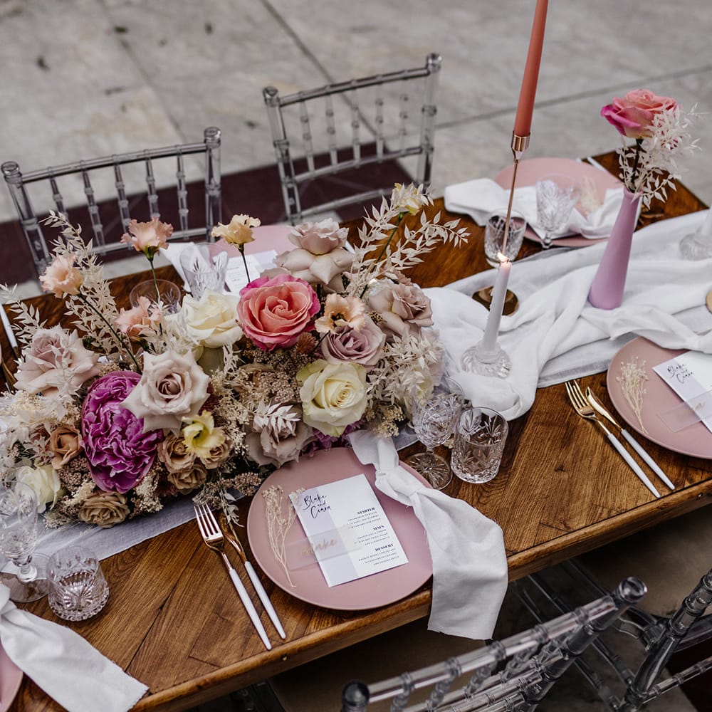 Elegant tablescape decor with pink tableware, cut glass, taper candles and pink floral arrangements 