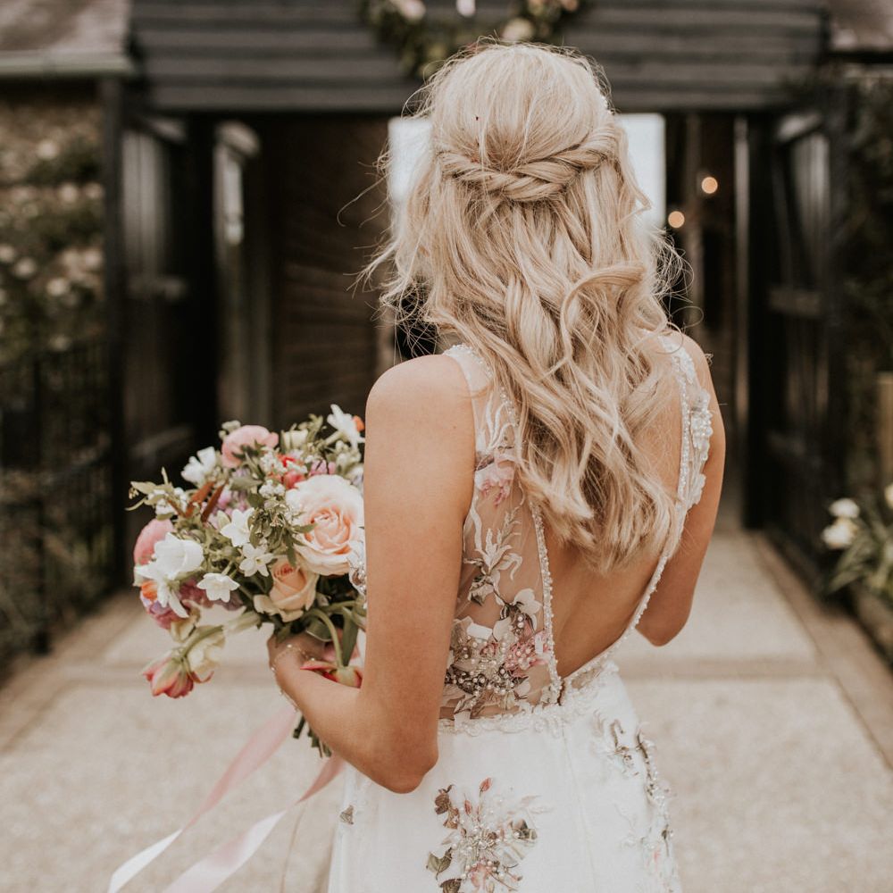 Bride in a floral embroidered wedding dress with a half up half down wedding hairstyle 