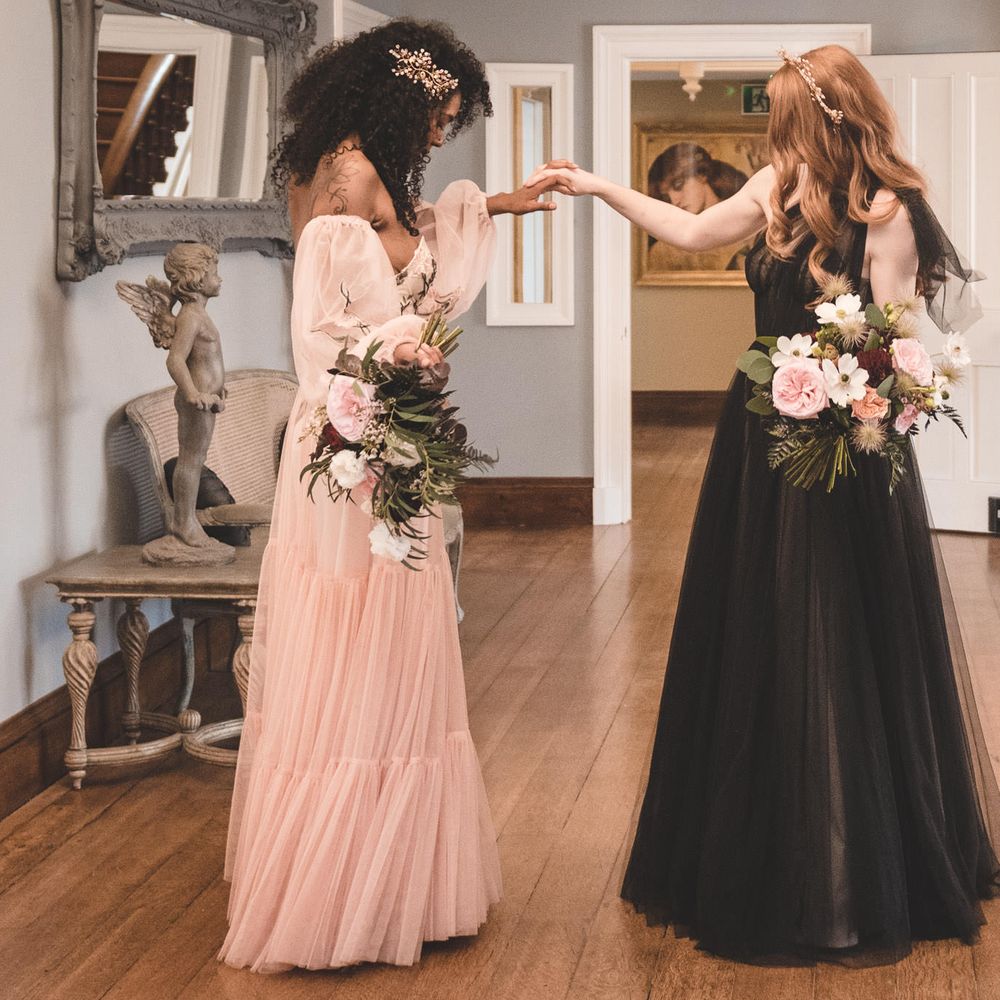 Two brides seeing each other for the first time in their blush pink and black coloured wedding dresses for an autism marriage