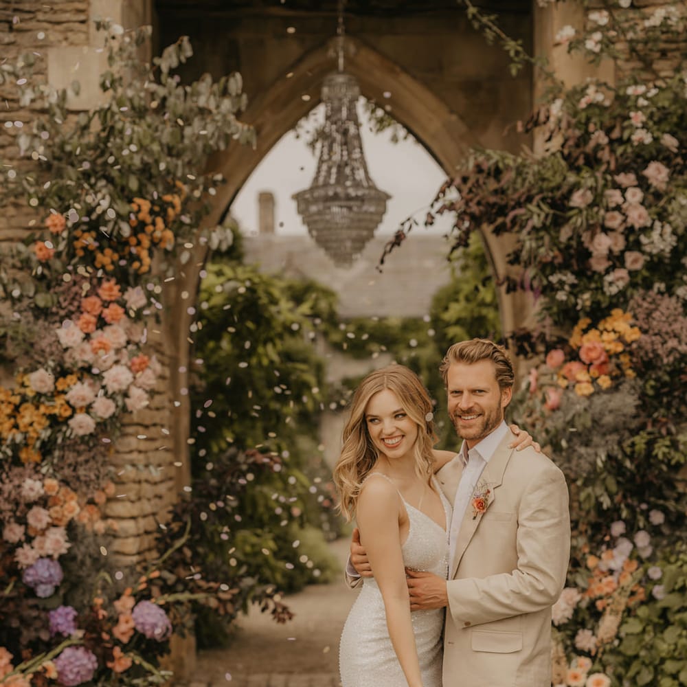 Confetti moment at the Castle Arch at Euridge Manor with chandelier. The bride wears Made With Love dresses and the groom a beige suit 