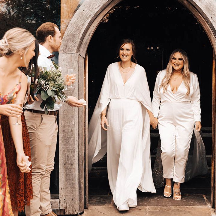 Brides leave wedding ceremony through wooden arched doorway