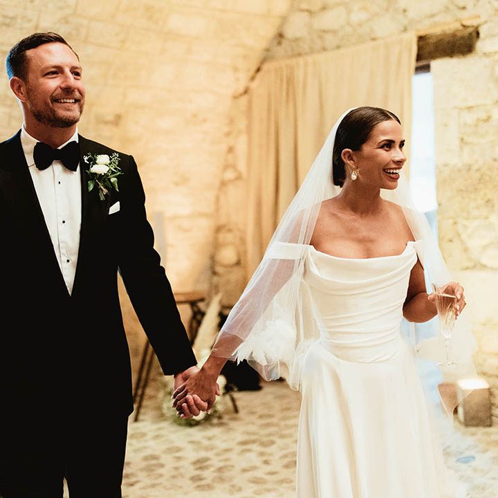 Bride & groom hold hands on their wedding day as they walk with one another