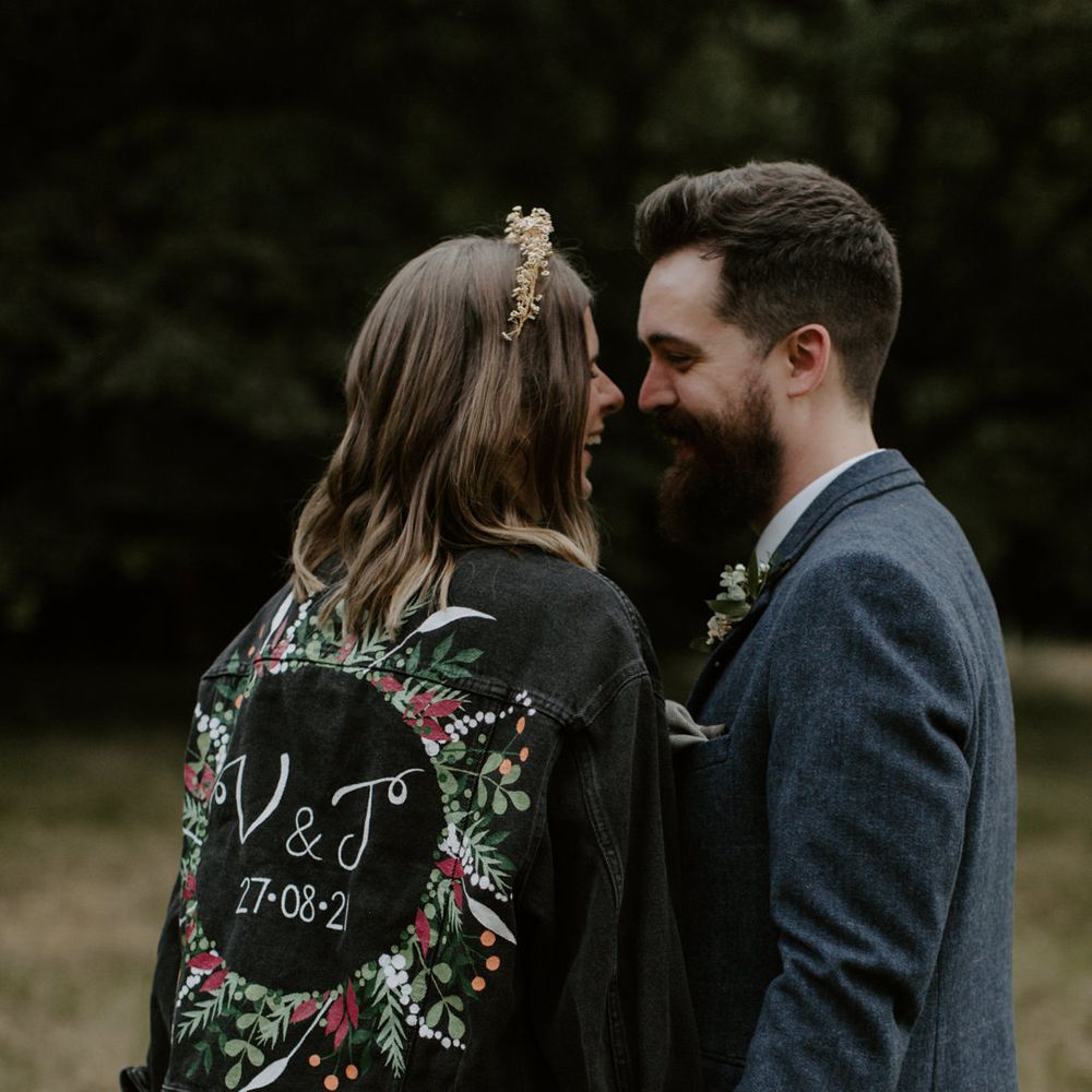 Bride kisses her groom whilst wearing personalised denim jacket for wedding day