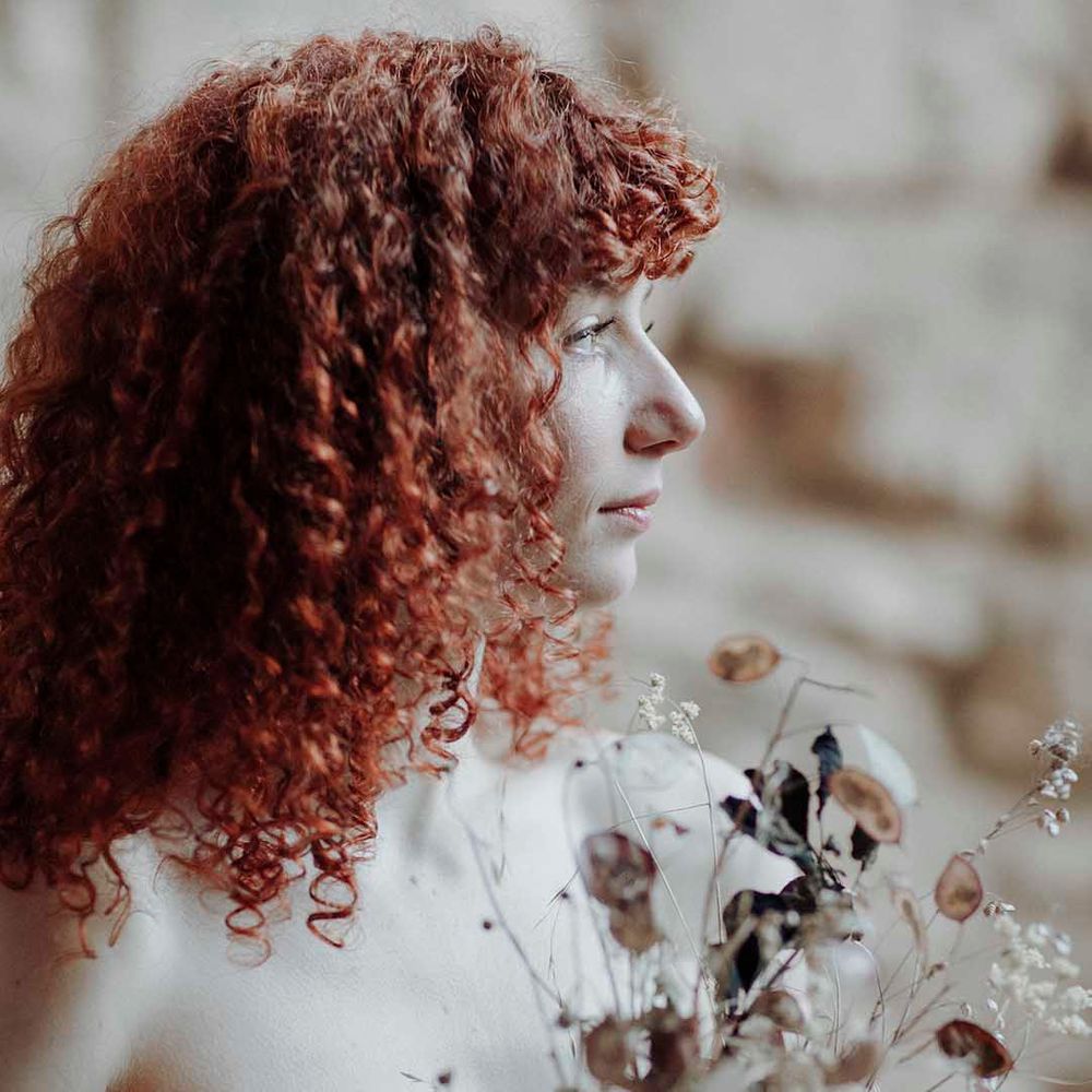 Bride with naturally curly red hair holding a dried flower wedding bouquet at Blackfriars Priory wedding inspiration 