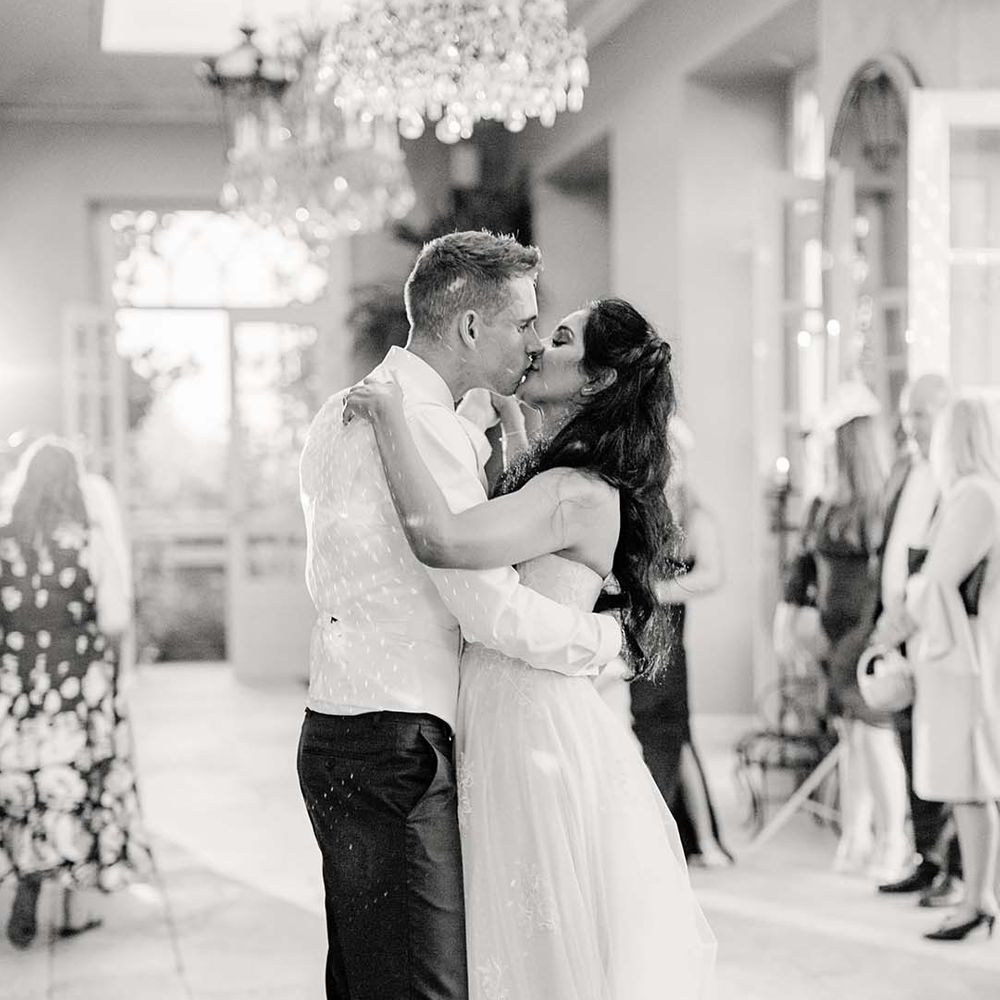 Bride & groom kiss in black & white image on their wedding day in The Orangery at Euridge Manor
