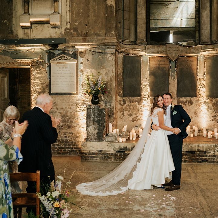 Bride and groom at industrial wedding venue with bride wearing high low skirt and lacy top with long lace veil 