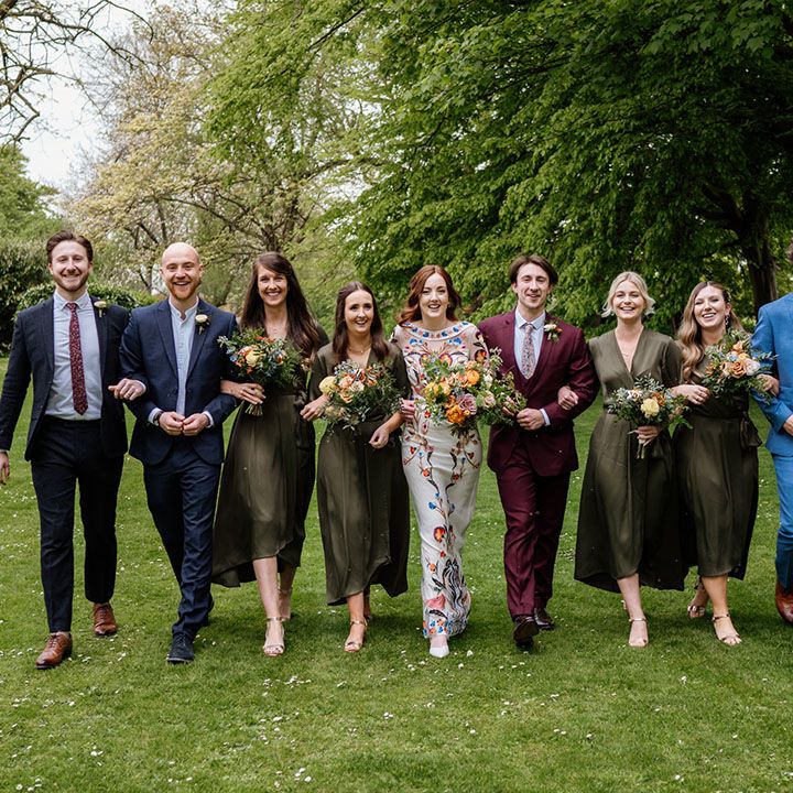 Wedding party wearing different coloured suits, a colourful wedding dress and bridesmaids in matching green wrap dress
