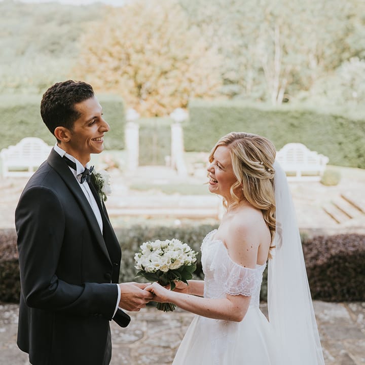 Bride and groom hold hands with groom in black tie and bride in off the shoulder wedding dress