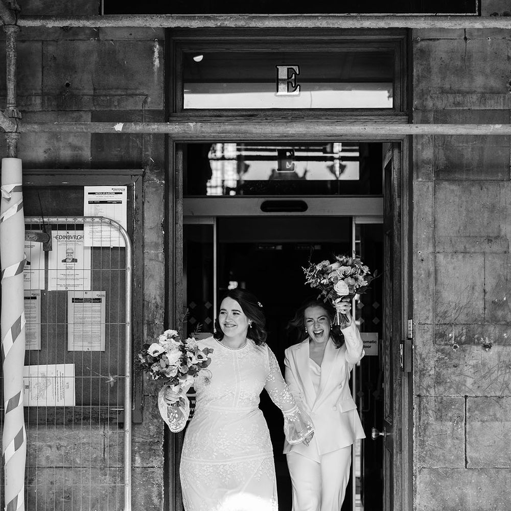 Brides celebrate as they leave wedding ceremony in black and white image