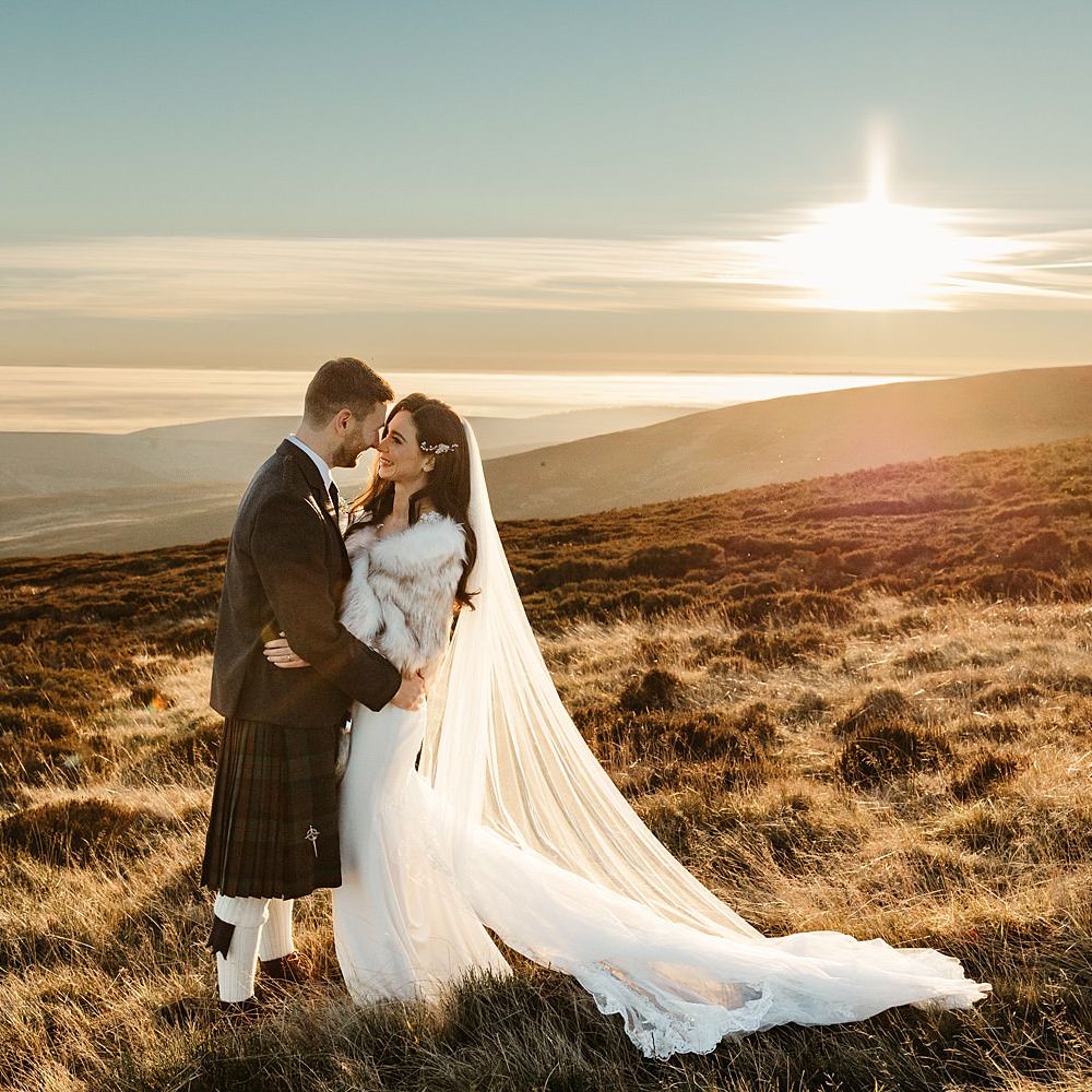 Bride & groom stand outdoors on hills during sunset in Scotland for winter wedding 