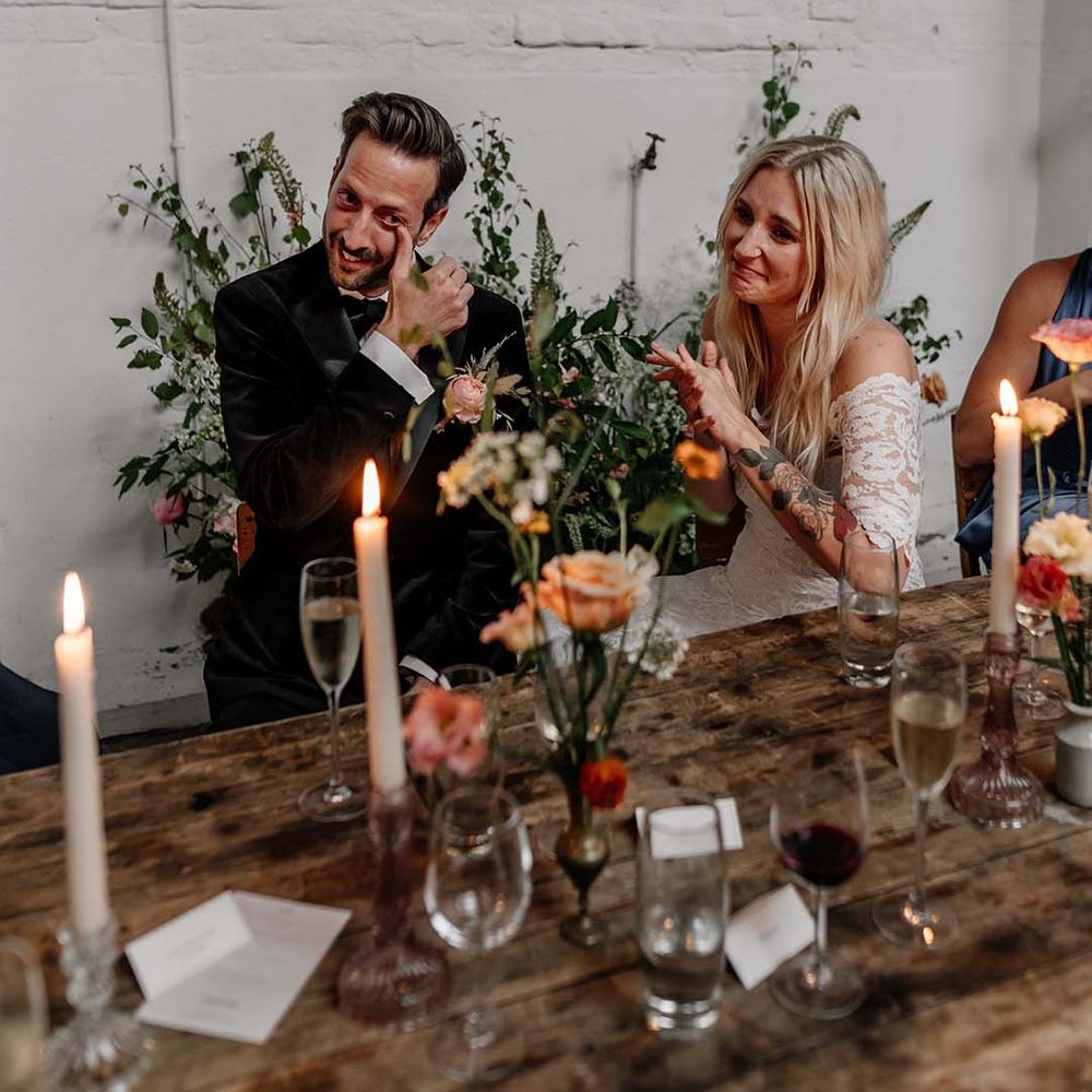 Bride in boho two piece lace bridal outfit and groom in dark tux with bowtie at modern stylish wedding reception
