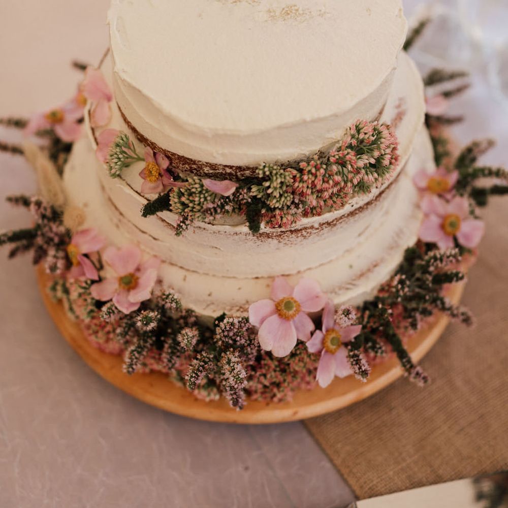 Two tier wedding cake with frosting and pink flowers 