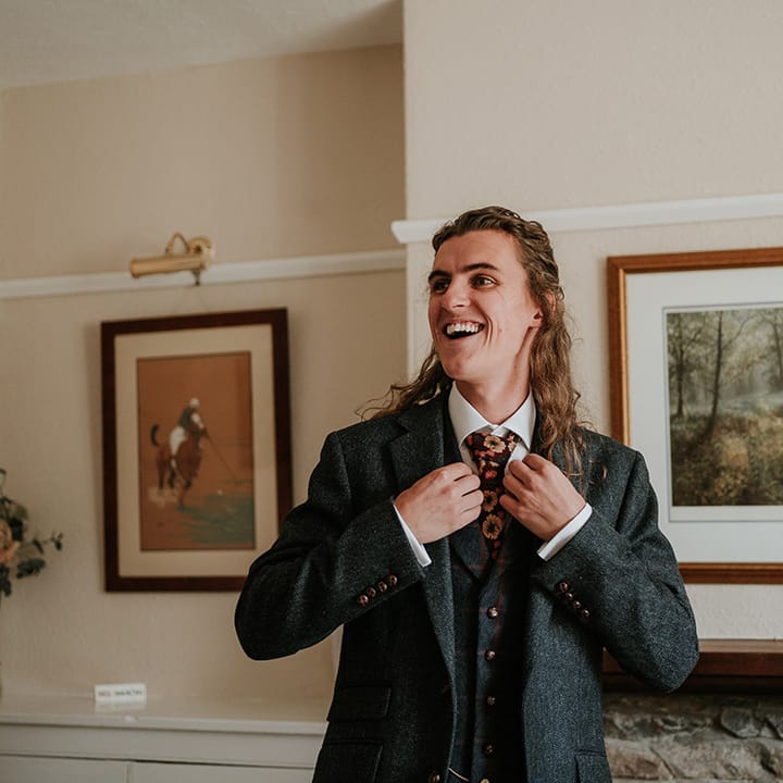 Groom in dark grey three piece suit and burgundy flower patterned tie 