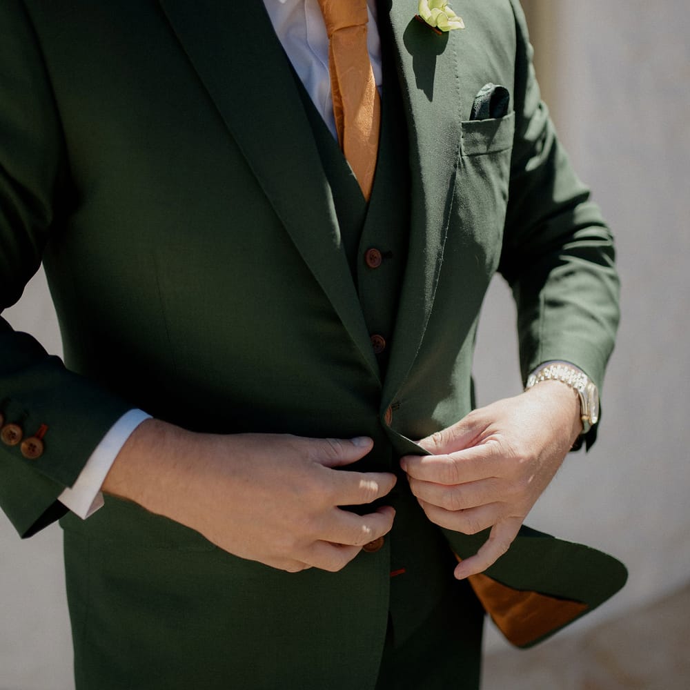 Dark green groom's suit with orange tie at destination wedding 