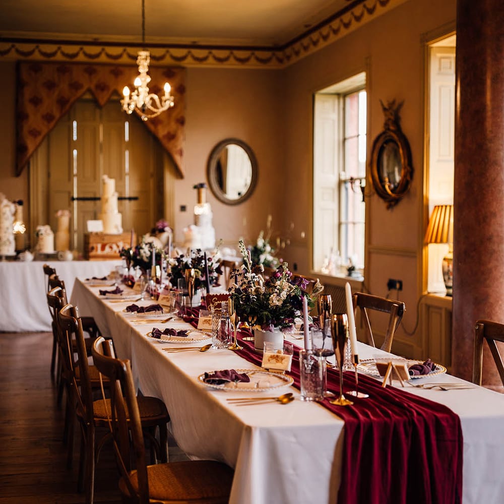 Winter wedding with dark red wedding tablescape with gold rimmed glasses and charger plates 