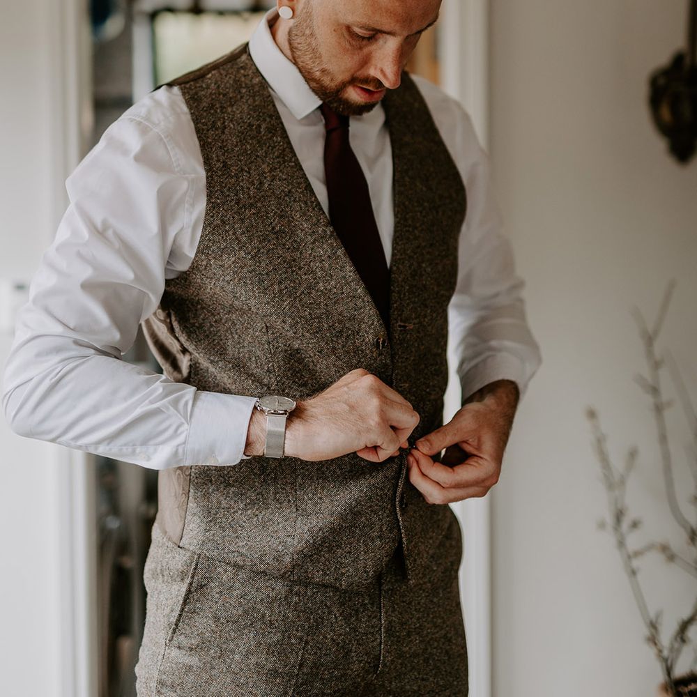 The groom in a grey wedding suit gets ready for the wedding day 